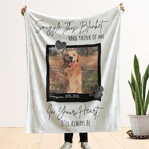 May include: White blanket with a photo of a golden retriever dog, a black heart, and paw prints. The blanket has the text "Snuggle This Blanket And Think Of Me" and "In Your Heart I'll Always Be". The dog's name and dates are also printed on the blanket.