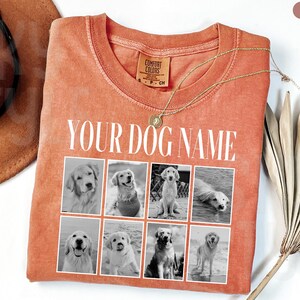 May include: A rust-coloured crew neck t-shirt featuring the text YOUR DOG NAME in white capital letters above a grid of eight black and white photographs of dogs. The shirt has a Comfort Colors brand label at the inner neckline.