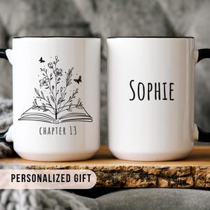 May include: White ceramic mug with a black handle and rim. One side features a floral and butterfly design above the text "CHAPTER 13". The other side displays the name "Sophie". The mug is a personalized gift.