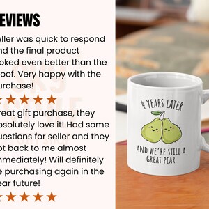 K&ouml;nnte beinhalten: Wei&szlig;e Keramik-Tasse mit Henkel. Die Tasse zeigt ein Design mit zwei gr&uuml;nen Birnen und dem Text "4 YEARS LATER AND WE'RE STILL A GREAT PEAR".