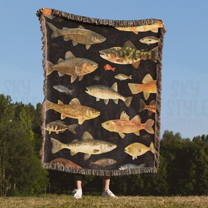 May include: A black woven throw blanket with a colorful pattern of various fish. The blanket features a variety of fish species, including trout, bass, and catfish, all rendered in a realistic style.