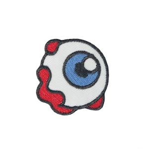 May include: A white eye with a blue iris and black pupil, with red dripping blood around it. The eye is embroidered on a white fabric patch.