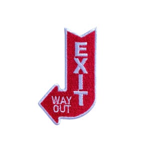 Può includere: Toppa ricamata rossa e bianca a forma di freccia con la scritta "EXIT" in verticale e "WAY OUT" nella freccia. La toppa ha un bordo bianco.