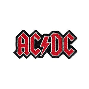 May include: Embroidered patch featuring the band name "AC/DC" in red, outlined in white, on a black background. The design includes a lightning bolt through the "C". The patch has a jagged border.