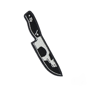 以下が含まれることがあります： 黒と白のナイフのデザインが施された刺繍パッチ。ナイフの刃にはスカルのグラフィックがあります。パッチは黒い縁取りがあり、衣類やアクセサリーへの適用に適しています。