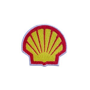 May include: A yellow and red embroidered patch in the shape of a seashell. The patch has a red border and a white outline. The interior of the shell is yellow with red lines radiating from the center.
