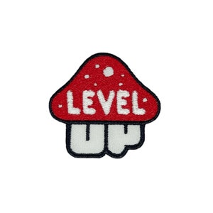 May include: Red and white embroidered patch shaped like a mushroom with the text "LEVEL UP" on the top.