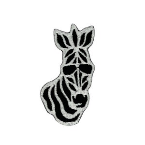 Puede incluir: Parche bordado en blanco y negro de una cebra con gafas de sol. La cabeza de la cebra está mirando hacia adelante y las rayas son visibles en la cara y el cuello.