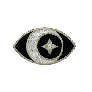 May include: A black and white embroidered eye patch with a crescent moon and a star in the center.