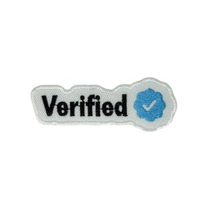 Pode incluir: Patch branco com a palavra "Verified" em texto preto. Um símbolo de visto azul está à direita. O patch tem uma borda branca.