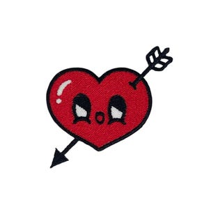 Puede incluir: Corazón rojo con una cara de dibujos animados y una flecha negra que lo atraviesa.