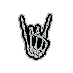 May include: A black and white embroidered iron-on patch of a skeleton hand making the rock and roll hand gesture.