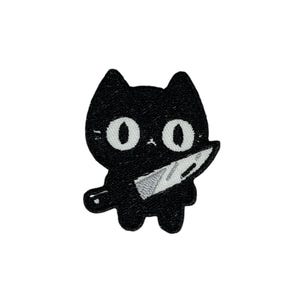 Pode incluir: Etiqueta bordada preta para passar a ferro de um gato de desenho animado a segurar uma faca. O gato tem olhos grandes brancos e um design simples.