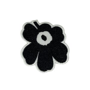 May include: Black and white embroidered flower patch. The patch features a large black flower with a white center and a white border. The flower has a simple, modern design and is likely intended for decorative use on clothing or accessories.