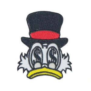 May include: An embroidered patch of a cartoon duck wearing a black top hat with a red band. The duck has white feathers, a yellow beak, and dollar signs in its eyes.