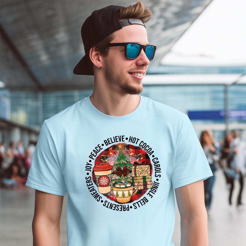 A man wearing a light blue t-shirt with a circular design on it, smiling and wearing sunglasses.