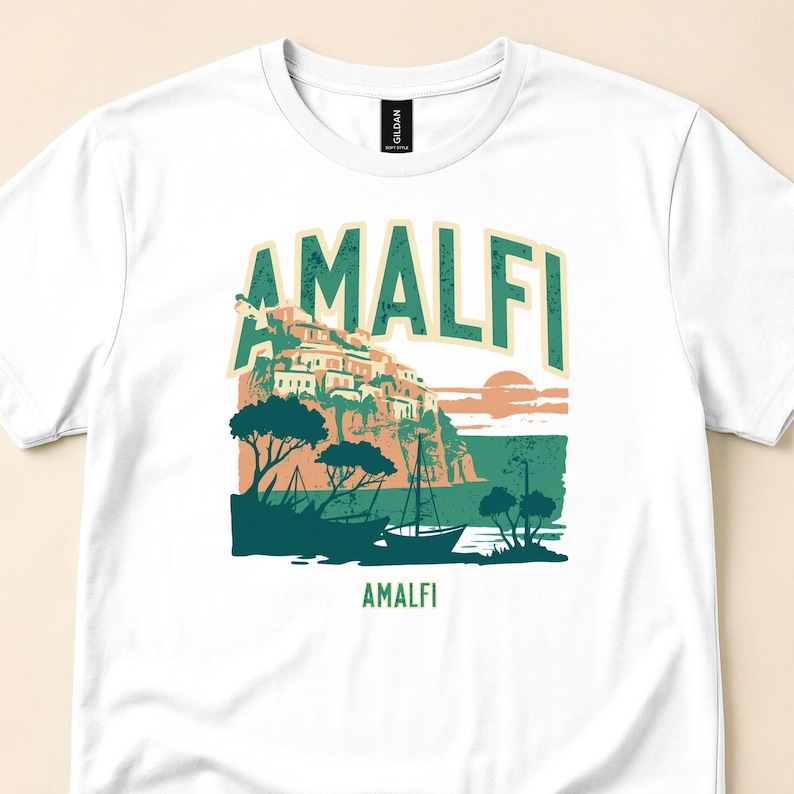 Close-up of white T-shirt with Amalfi lettering above cliffside houses, trees and sea.