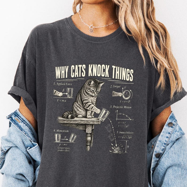 Model in charcoal Why Cats Knock Things tee with cat and physics diagrams.