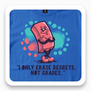 May include: A royal blue t-shirt featuring a cartoon pink eraser character with arms crossed and a smug expression. Behind the character are teal and coral circular shapes. The text reads, "I ONLY ERASE REGRETS, NOT GRADES." in dark blue.
