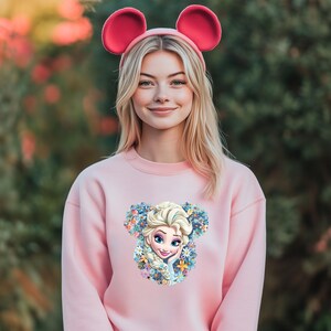 a woman wearing a pink sweatshirt with ears on her head