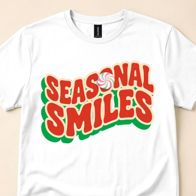 Close view of a white tee with red Seasonal Smiles lettering, green shadows and a peppermint swirl.