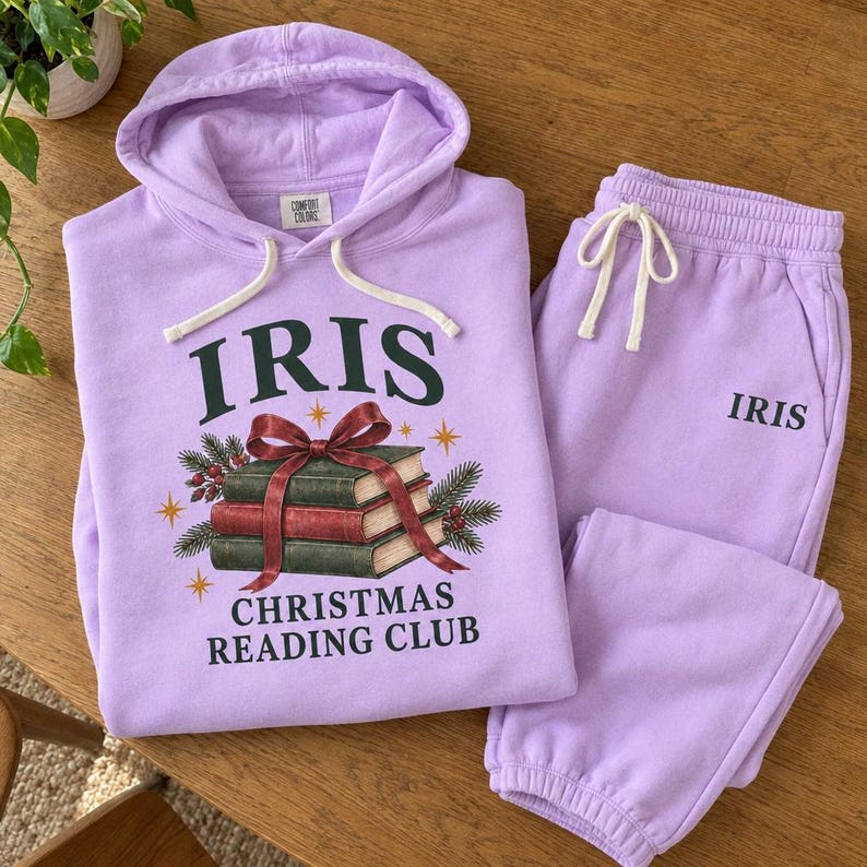 Folded lilac hoodie and joggers with ribbon tied books and Iris lettering.