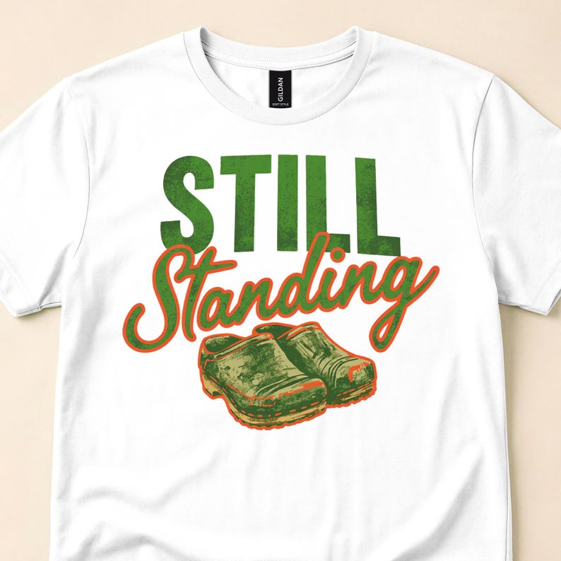 Close view of a white T-shirt with Still Standing lettering and worn shoes.