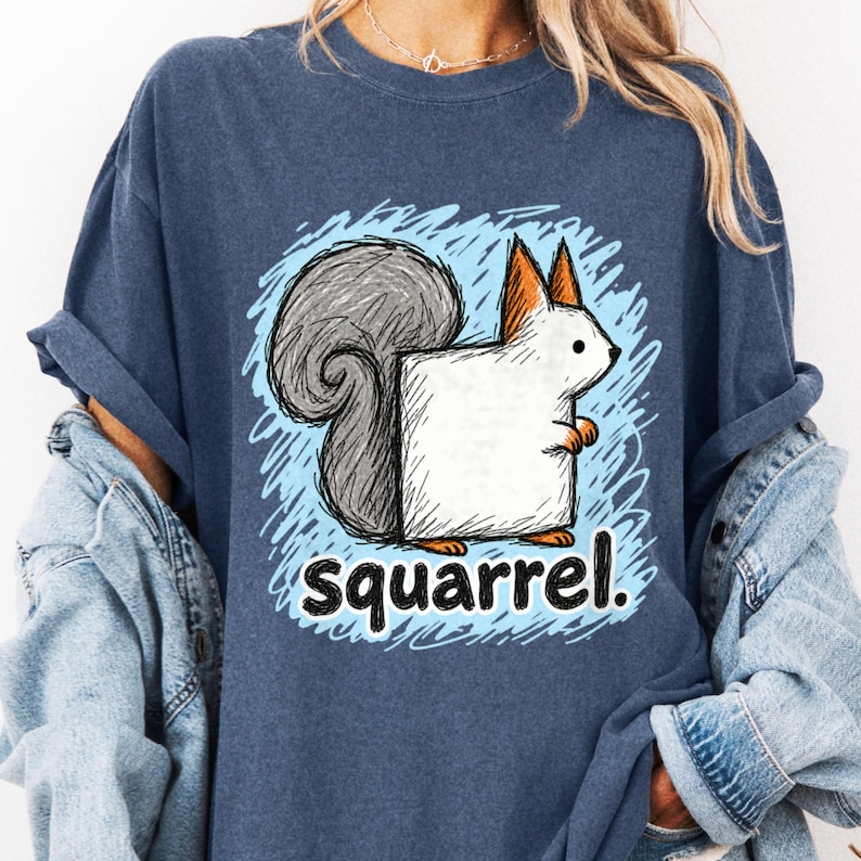 Close-up of a model in a navy tee with a square-bodied squirrel, curled gray tail, blue scribbles and "squarrel." text.