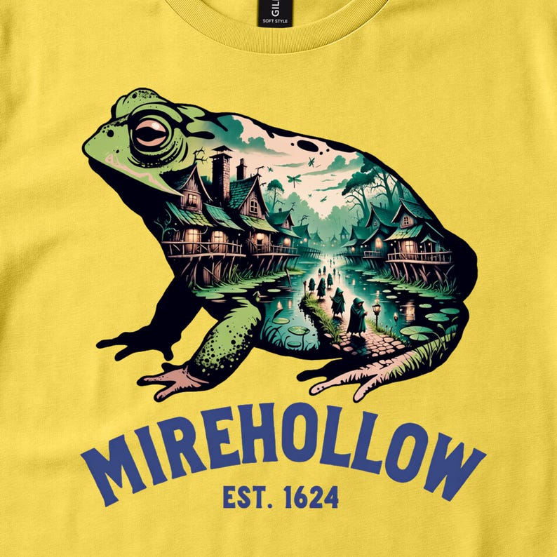 Close view of a yellow Mirehollow shirt with a village and waterway inside a green toad silhouette