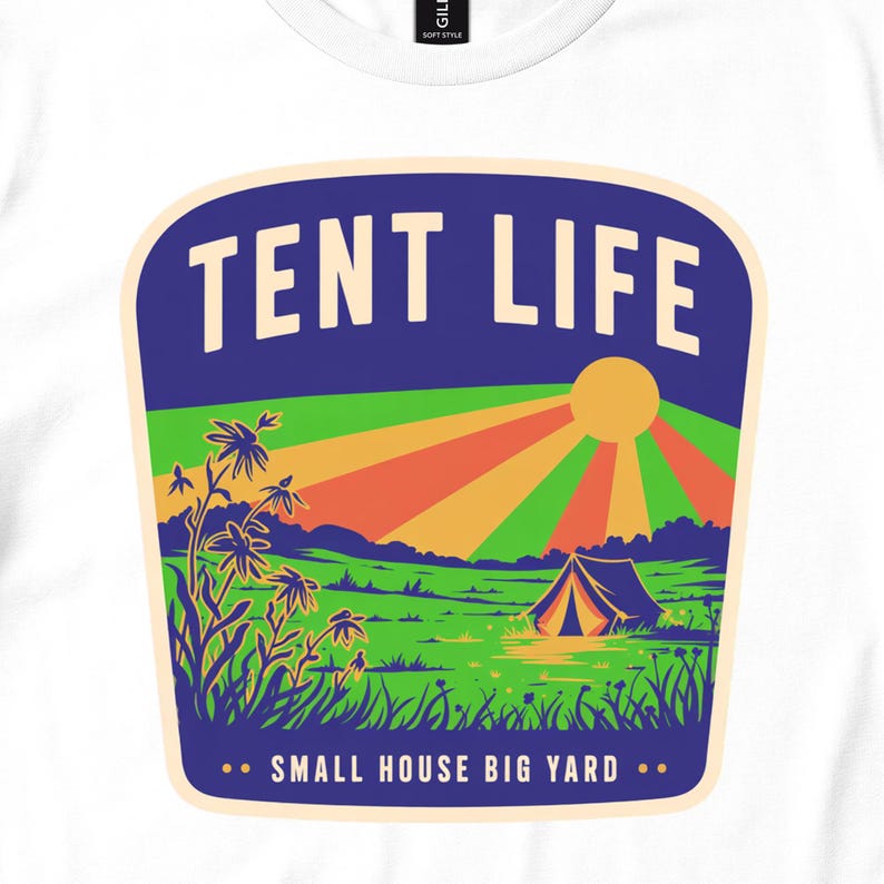 Close view of white T-shirt with a colorful Tent Life badge showing a meadow tent and striped sun rays.