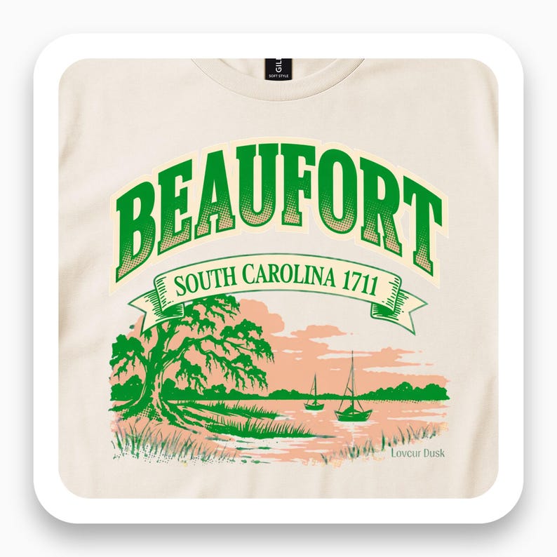 Close view of a cream T-shirt with green Beaufort lettering and a coastal landscape.