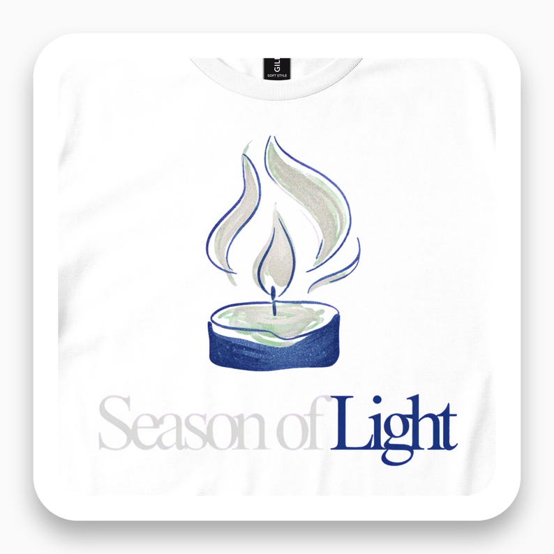 Close view of a white T-shirt with an outlined candle flame and Season of Light lettering.