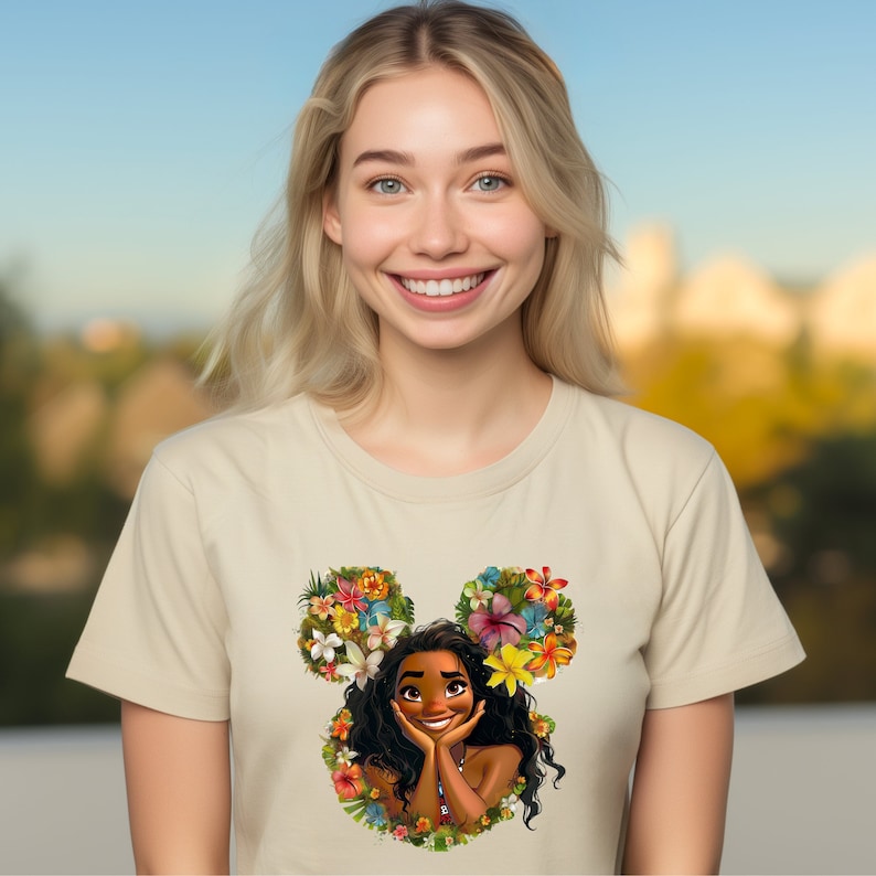 Puede incluir: Una camiseta beige con un dise&ntilde;o floral de Mickey Mouse con una caricatura de Moana de la pel&iacute;cula de Disney Moana. El dise&ntilde;o est&aacute; hecho de flores y hojas tropicales.
