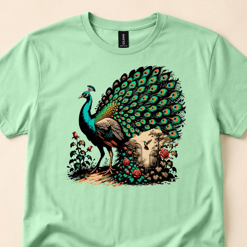 Mint tee close-up with a peacock spreading its tail among flowers and rocks.