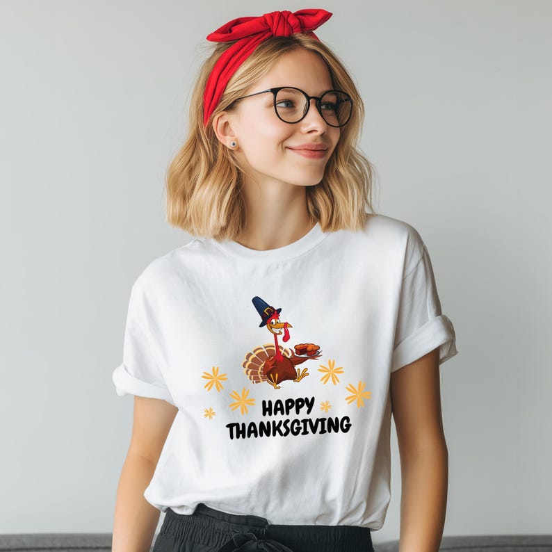 A young woman wearing a white t-shirt with a graphic of a turkey wearing a witch's hat and the text "Happy Thanksgiving" printed on it.
