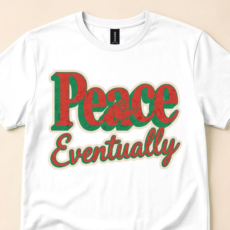 White T-shirt close-up with red-and-green Peace Eventually lettering with a cream outline.