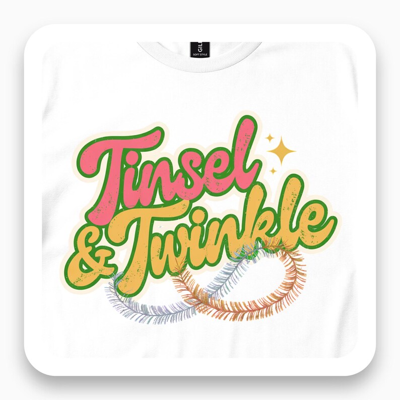 White T-shirt close-up with pink and yellow Tinsel & Twinkle script, sparkles and looping tinsel.