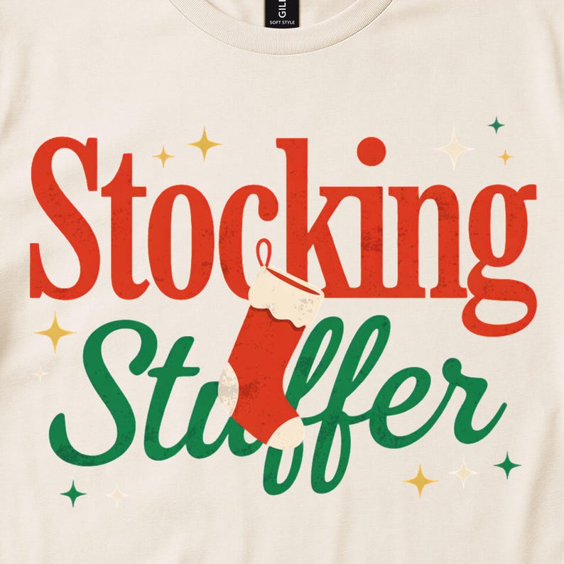 Cream shirt close-up with Stocking Stuffer lettering, a red stocking and small stars.
