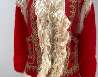 May include: A red and green embroidered vest with a white faux fur collar and trim. The vest has a long, flowing style and is perfect for a vintage or bohemian look.