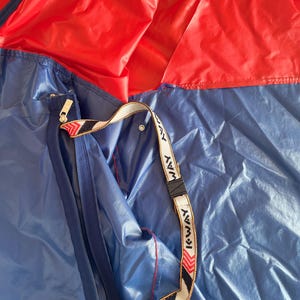 May include: A blue and red nylon tent with a zippered pocket and a K-Way branded strap.