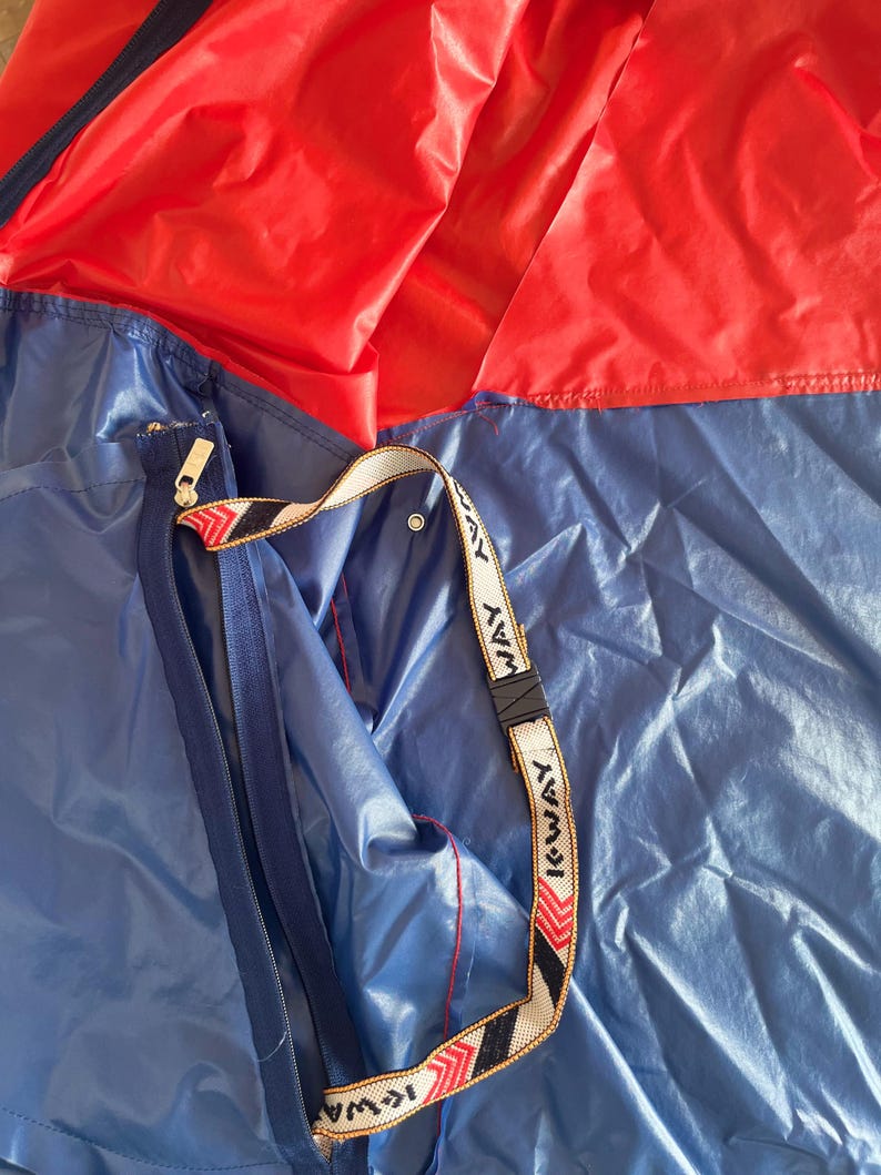 May include: A blue and red nylon tent with a zippered pocket and a K-Way branded strap.