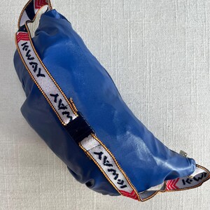 May include: A blue fanny pack with a white and red strap that says "AWAY" in white and yellow lettering.