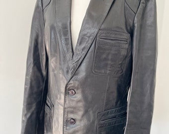 May include: A black leather blazer with a classic design. It features a notched lapel, two button closure, and two flap pockets.