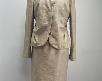 May include: A beige skirt suit with a long-sleeved jacket and a knee-length skirt.