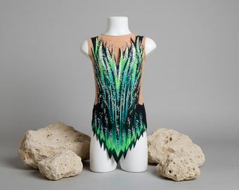 May include: A sleeveless leotard with a green and black design, displayed on a white mannequin. The leotard features a pattern of green blades with white accents. The mannequin is positioned in front of a gray background with three beige rocks.