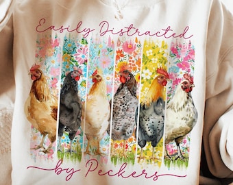 May include: Cream-colored sweatshirt with the text "Easily Distracted by Peckers" in pink script. The design features six watercolor chickens in front of colorful floral stripes. A casual, comfortable top.