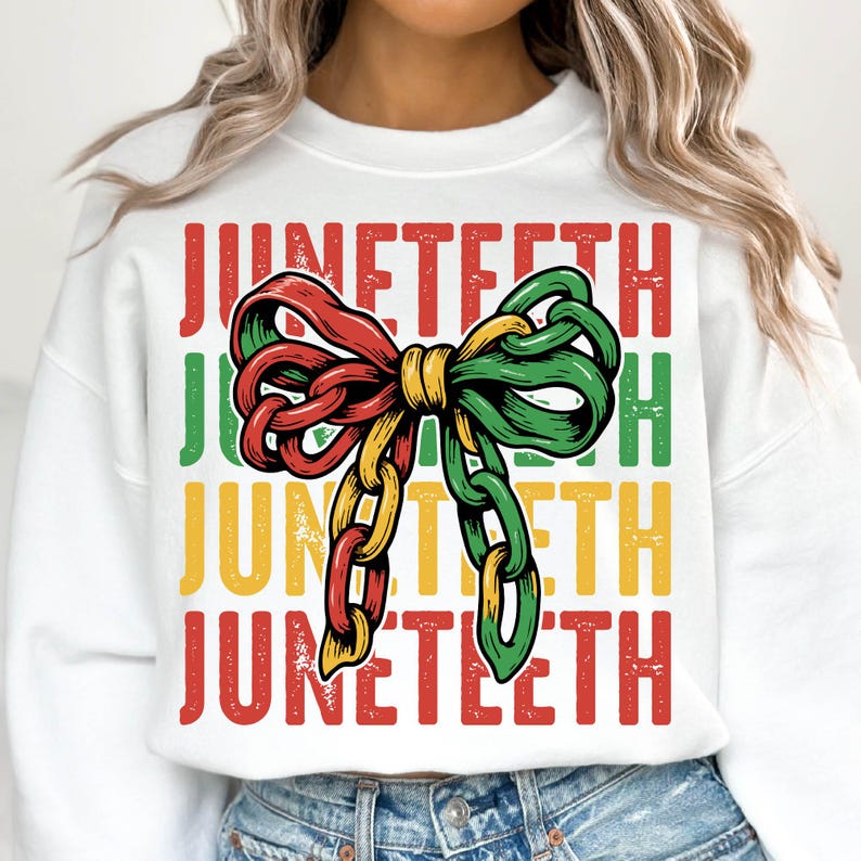 Może przedstawiać: Biała bluza z napisem "Juneteenth" w kolorze czerwonym, zielonym i ż&oacute;łtym. Centralnym elementem projektu jest kokarda w kształcie łańcucha w tych samych kolorach. Bluza ma swobodny styl.
