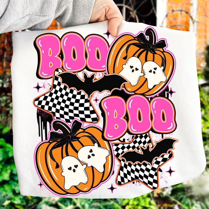 Puede incluir: Sudadera blanca con tem&aacute;tica de Halloween con la palabra "BOO" en letras rosas. El dise&ntilde;o incluye calabazas naranjas, fantasmas blancos, murci&eacute;lagos negros y estrellas a cuadros. Un gr&aacute;fico de Halloween divertido y festivo.