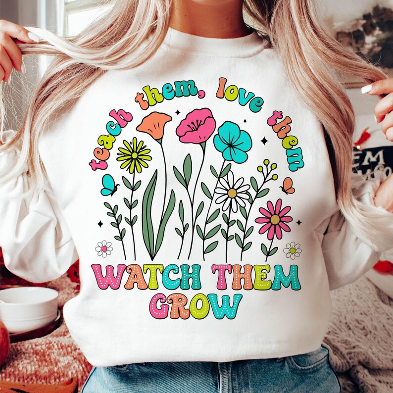 Puede incluir: Sudadera blanca con un gr&aacute;fico colorido de flores y el texto "Teach them, love them, watch them grow".