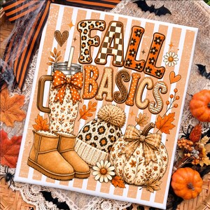May include: A rectangular sign featuring the text FALL BASICS in orange and brown patterns. The design includes a tumbler with a bow, a leopard print beanie with a pom-pom, and a pumpkin with a bow, all set against a white and orange striped background.